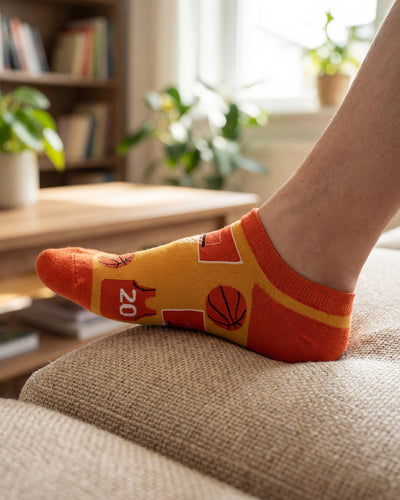 Socksop Basketball ankle socks at home — orange pair styled in casual indoor setting