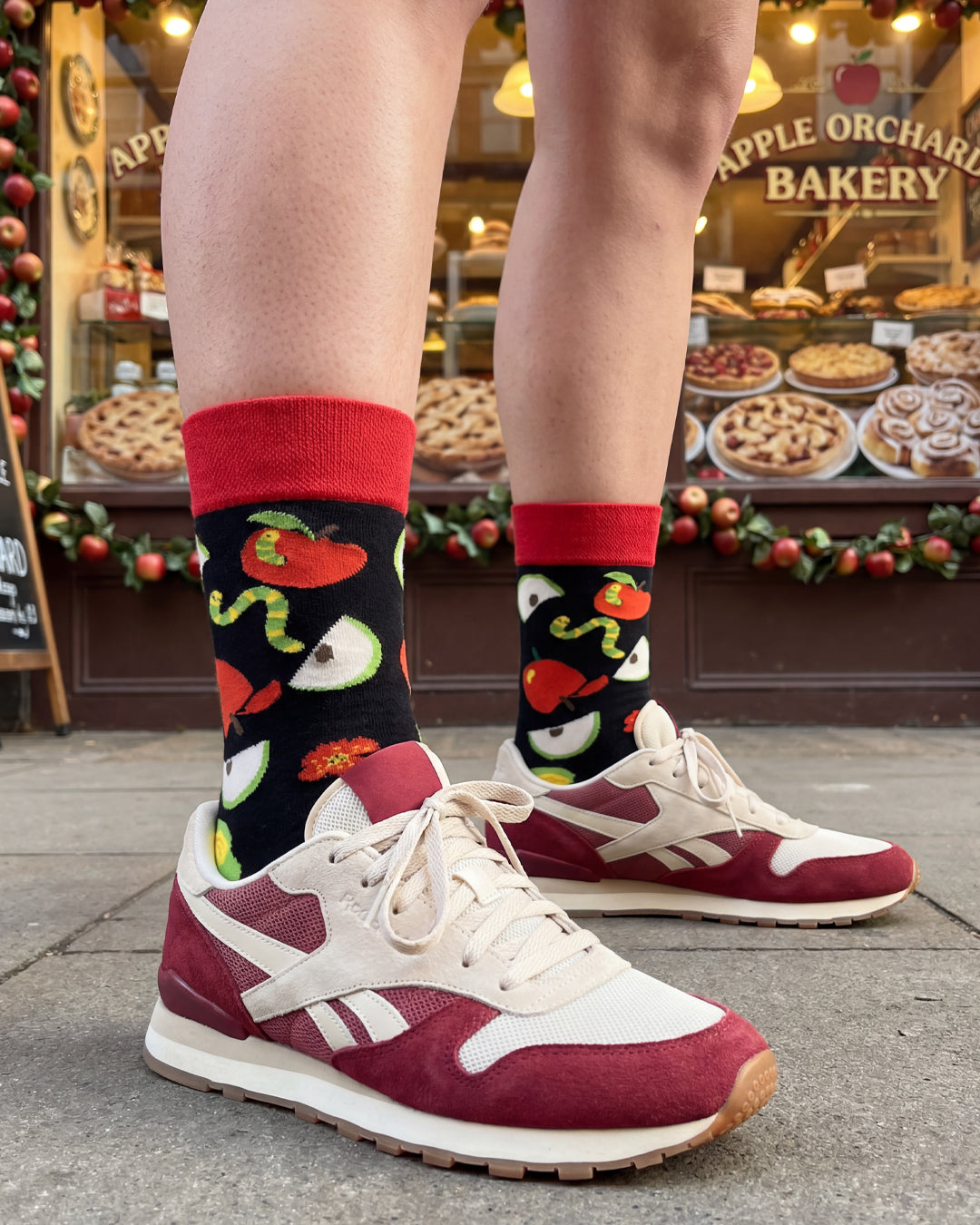 Socksop Apple crew socks worn outdoors — fruity novelty pattern paired with everyday shoes
