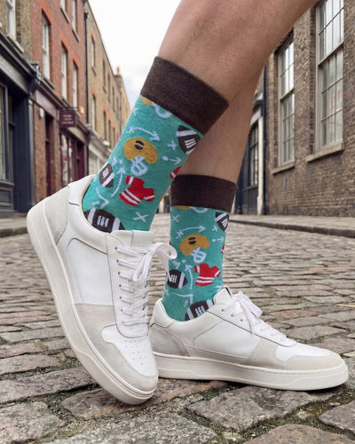 Socksop Football crew socks worn outdoors — sporty gridiron-themed pattern paired with sneakers