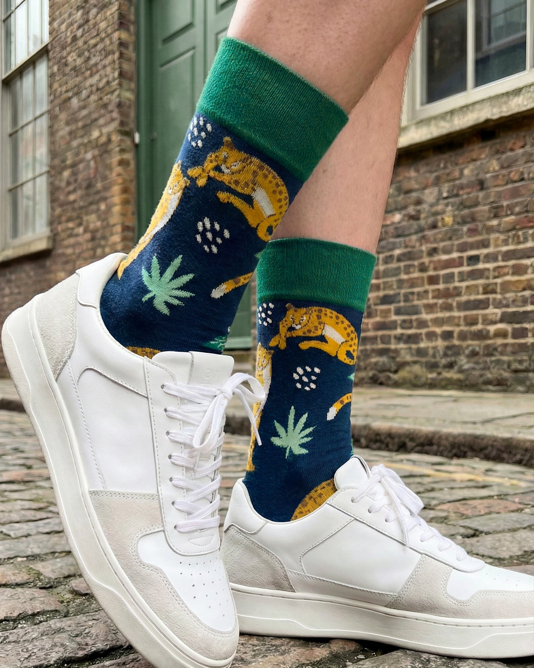 Socksop Forest crew socks worn outdoors — leopard and palm-leaf pattern paired with boots
