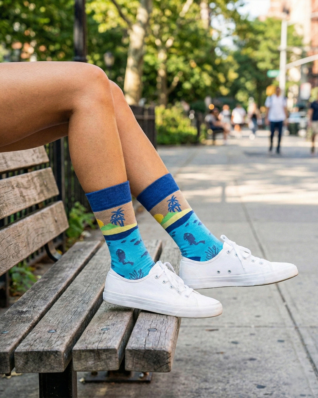 Socksop Summer crew socks worn outdoors — tropical beach scene pattern on a sunny day